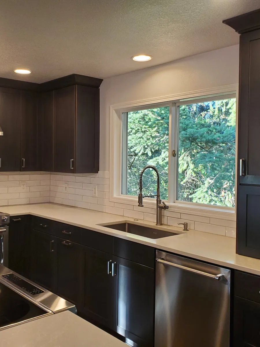 Kitchen sink under a bright window, with white subway tile and clear quartz counters