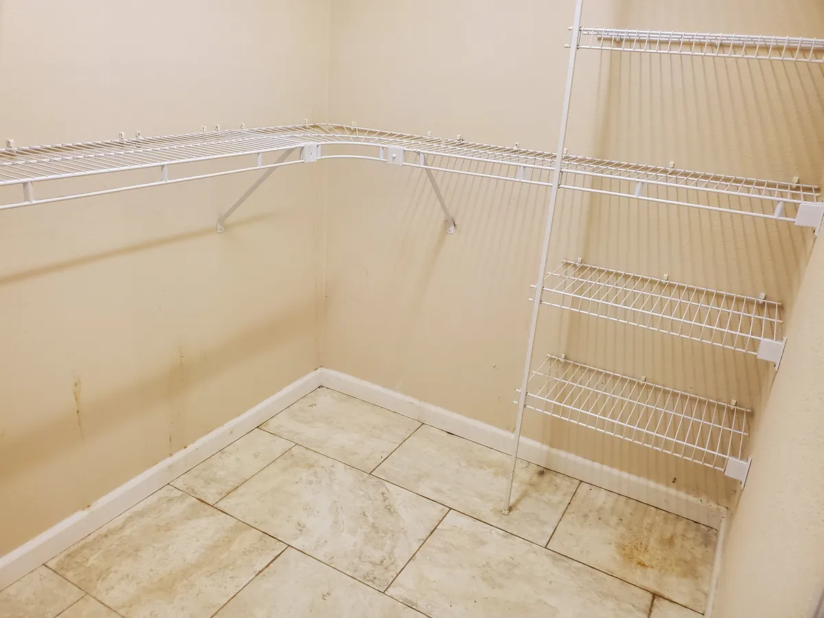 The same closet before cleaning, with dirty grout and dust