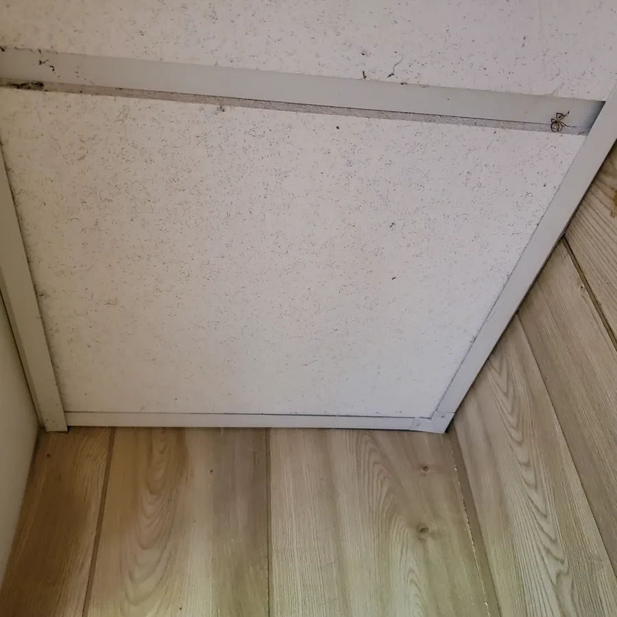 The same closet ceiling panel before cleaning, with dust and cobwebs