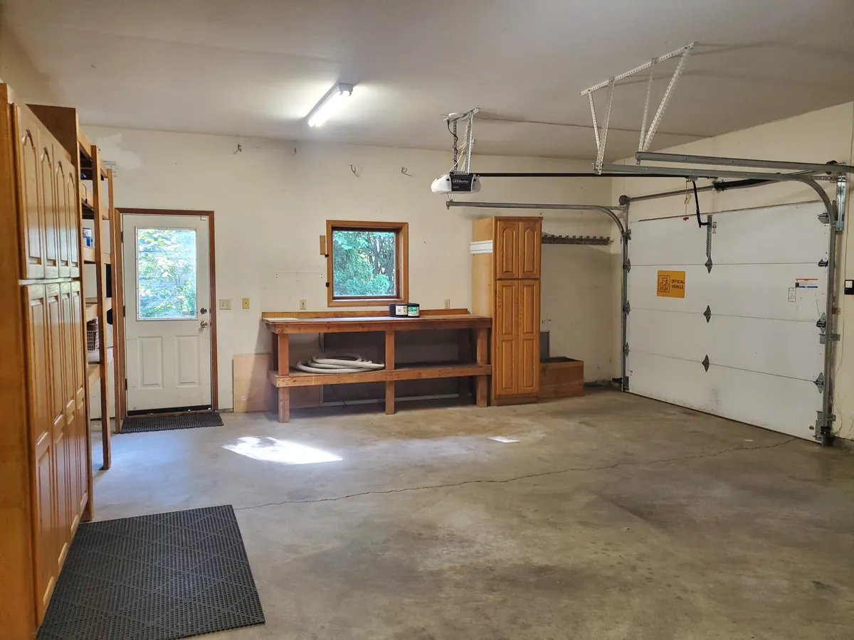 Garage with wood cabinets, a workbench, and a swept concrete floor