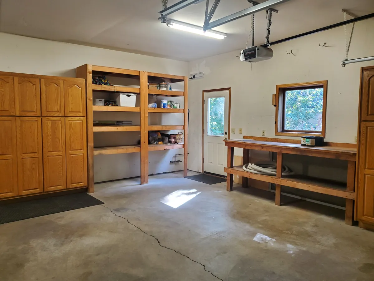 Garage with wood cabinets, open shelving, and a swept concrete floor