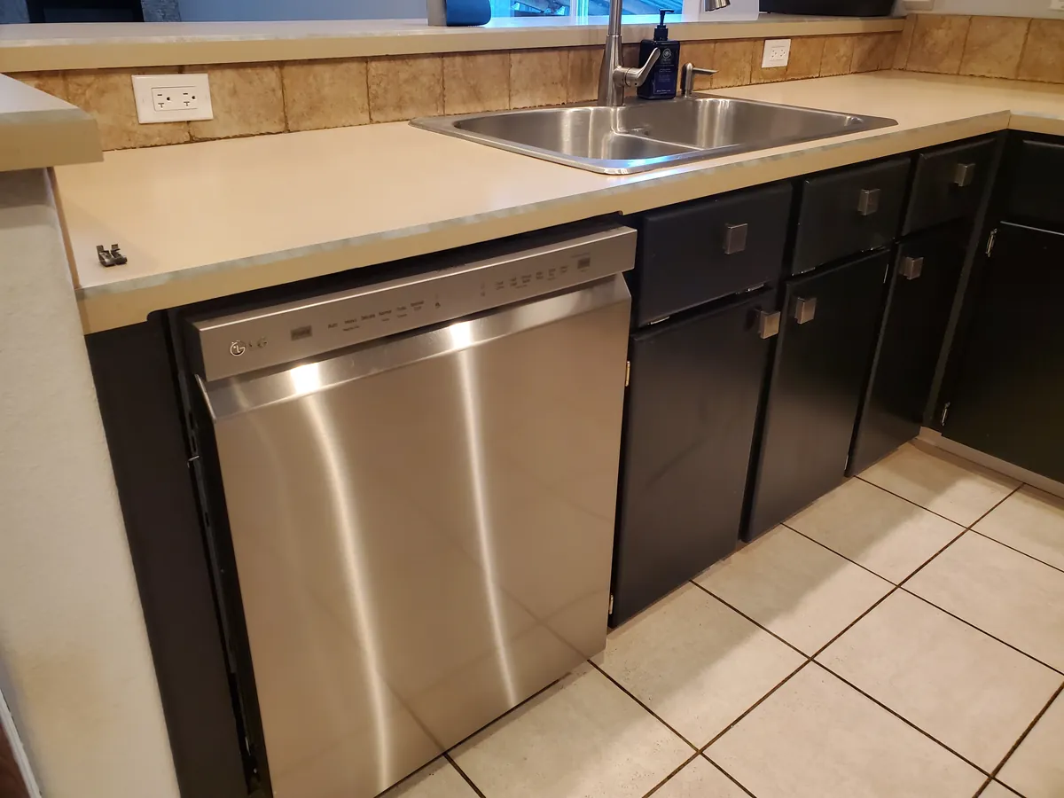 A kitchen corner after a clean: polished stainless dishwasher, clean counters and sink