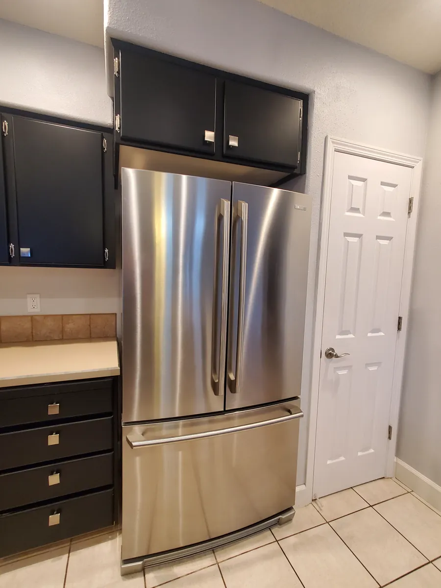 A gleaming stainless steel refrigerator and clean tile floor after a clean