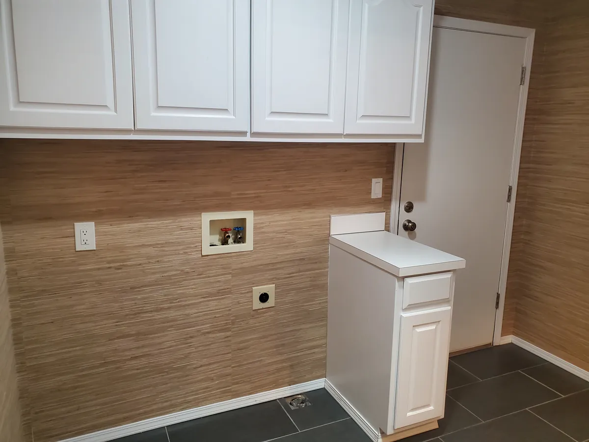 Laundry room with white upper cabinets and washer hookups