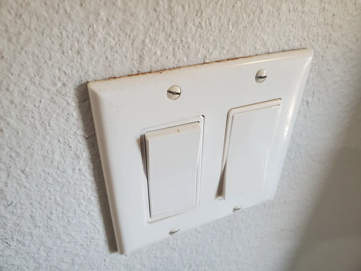 Light switch cover before cleaning, covered in grime