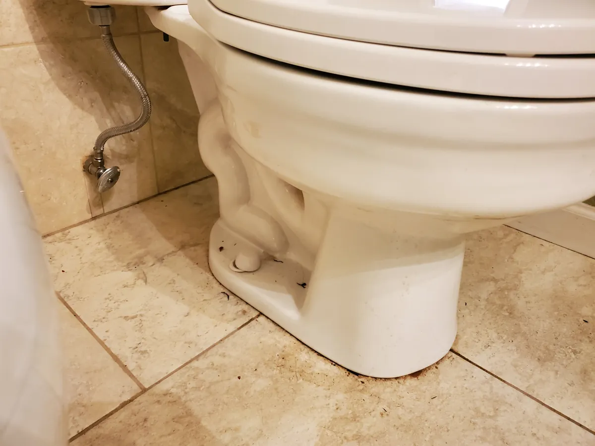 Toilet base and floor before cleaning, with buildup