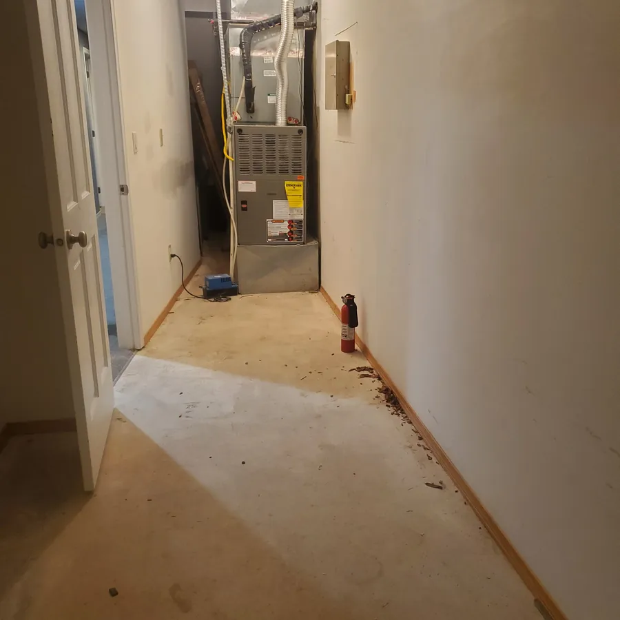 The same mechanical room before cleaning, with debris along the floor