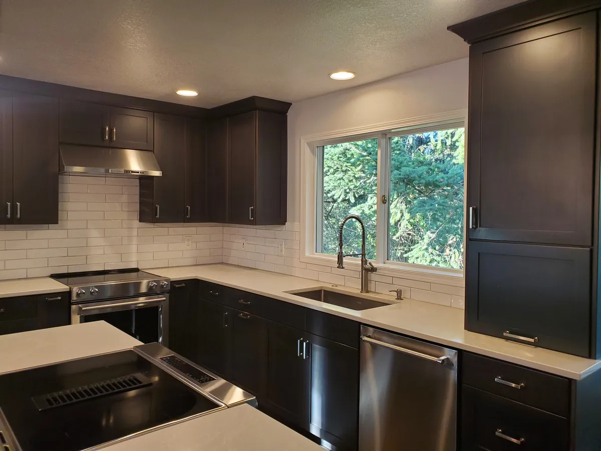Kitchen after a clean, with white subway tile, dark cabinetry, and a sink under the window