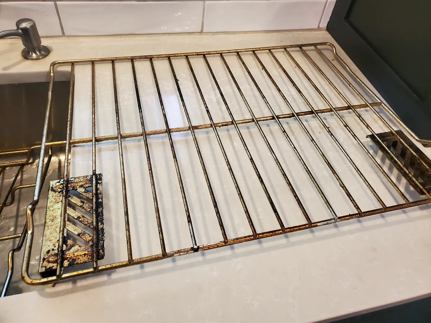 The same oven rack before cleaning, caked with burnt-on grease