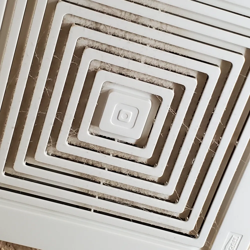 Bathroom exhaust vent before cleaning, caked with dust